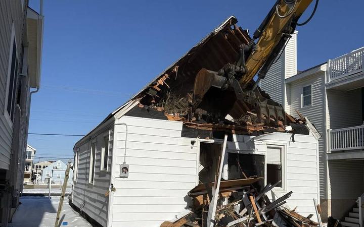 An excavator opening the roof of a house during demolition