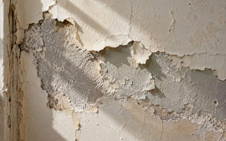 Layers of peeling paint and old plaster on an older interior wall