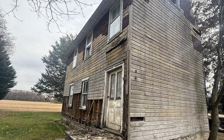 An abandoned wood frame farmhouse in a rural Salem County field