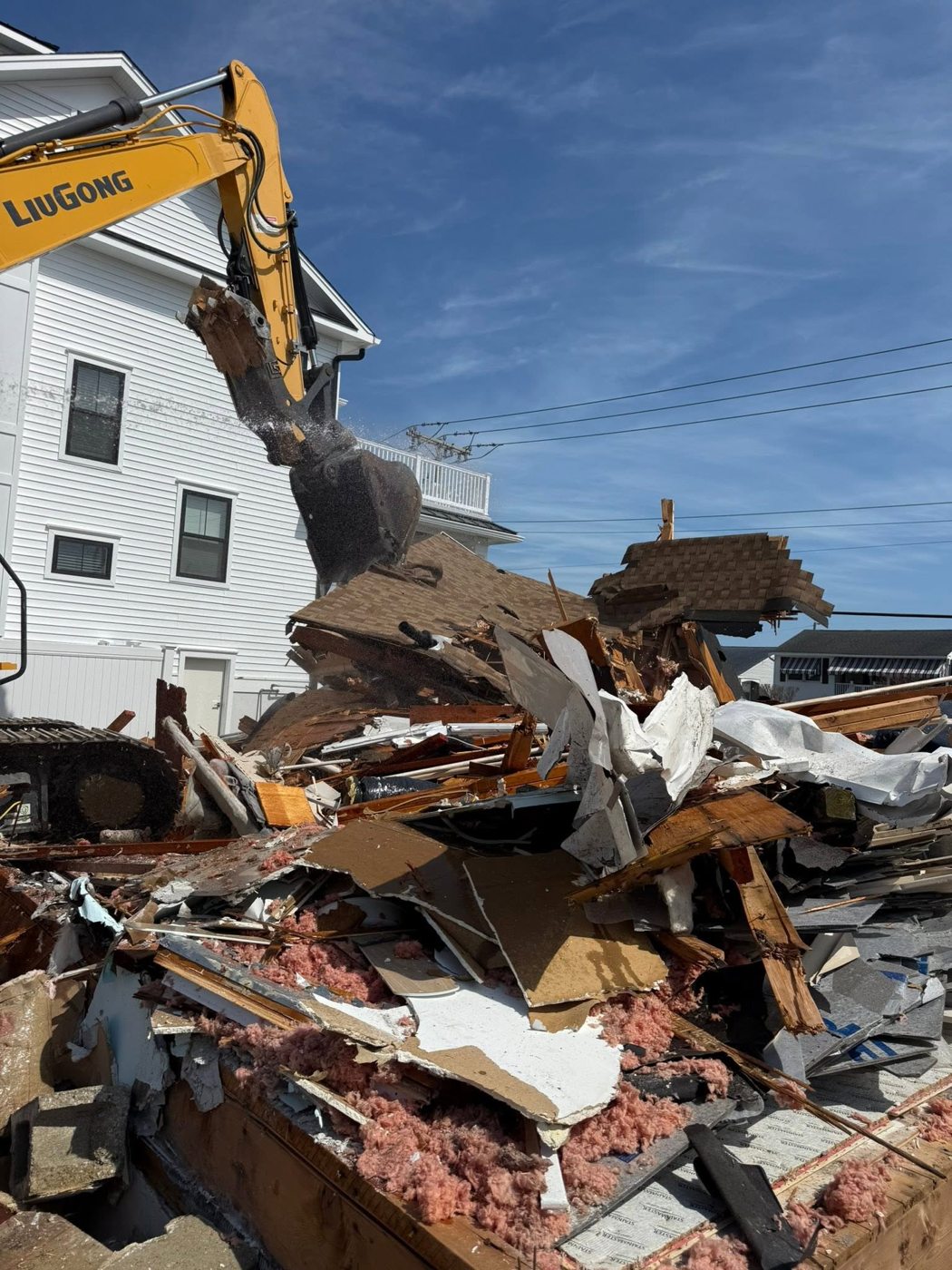 Excavator claw working through demolition debris at a shore teardown