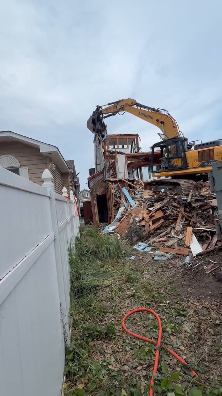 The frame of a two story home partly torn down with debris stacked below