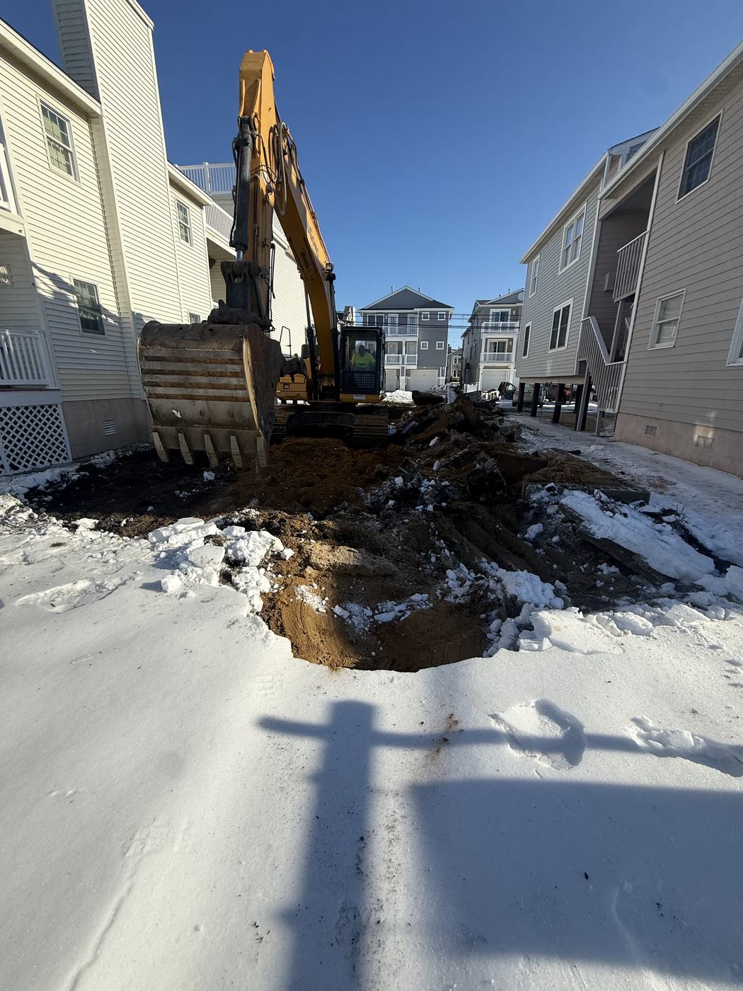 An excavator digging the old foundation out of the ground on a cleared lot